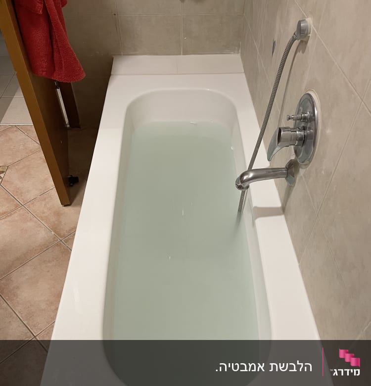 אמבטיה מלאה במים עם ברז ומקלחת יד